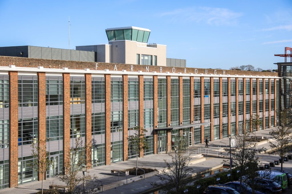 An office building with a control tower on the roof displays the sign "Farnborough"